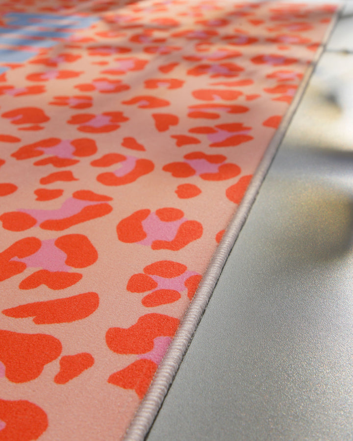 Nahaufnahme der sauber eingefassten Kante des Badteppichs Wet And Wild mit Pop-Art-Leopardenmuster.
