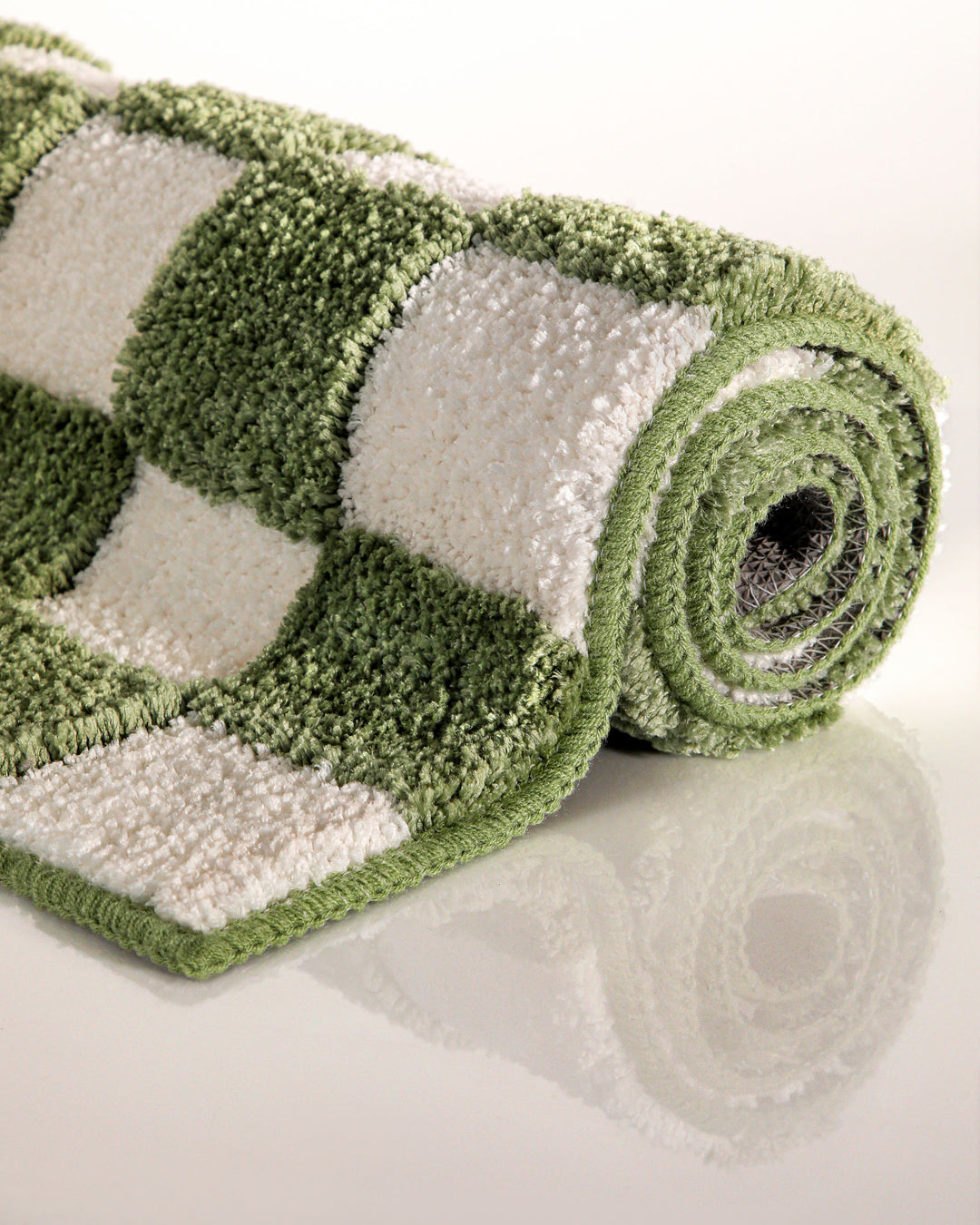 Badteppich Bobbi Grün aufgerollt auf hellem Hintergrund, Seitenansicht zeigt Florhöhe und Musterverlauf