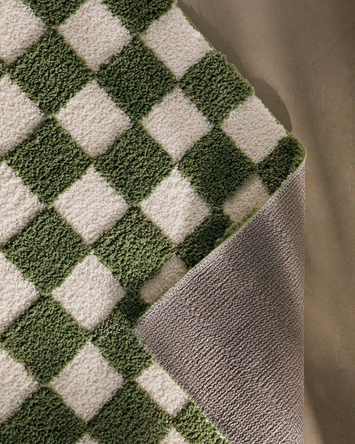 Badteppich Bobbi Grün im Badezimmer vor Holzbank auf hellem Boden, rechteckige Matte mit Schachbrettmuster