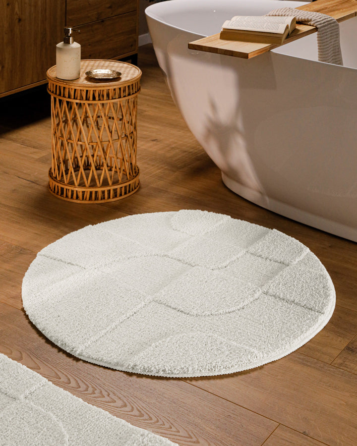 Runder Badteppich Davie Weiß im Badezimmer vor Badewanne auf Holzboden, strukturiertes Linienrelief im Flor sichtbar