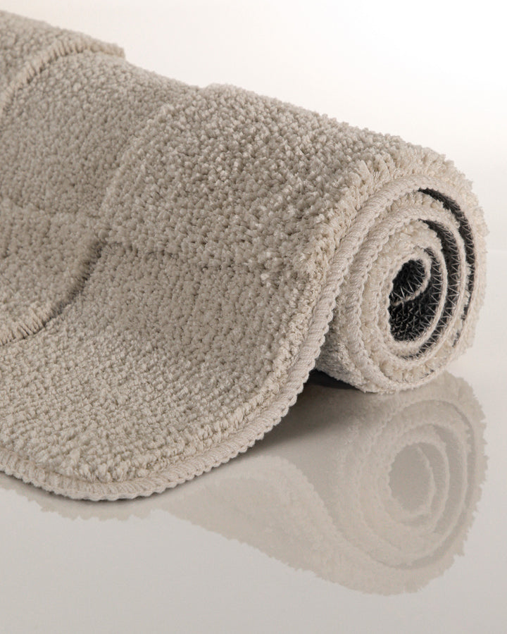 Badteppich Davie Grau aufgerollt auf hellem Hintergrund, Seitenansicht zeigt Florhöhe und Teppichkante