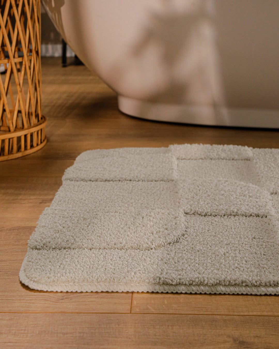 Badteppich Davie Grau runde Matte im Badezimmer vor Badewanne, Strukturmuster im Flor auf Holzboden sichtbar