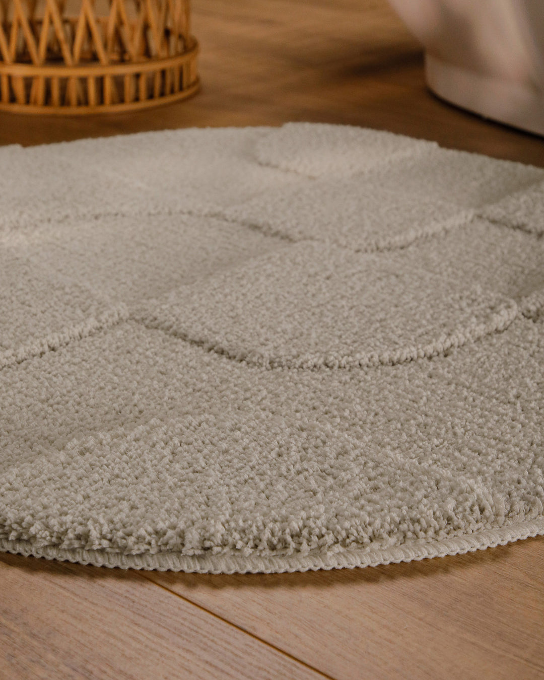 Badteppich Davie Grau rund im Badezimmer auf Holzboden neben Badewanne, Florstruktur und Linienrelief erkennbar