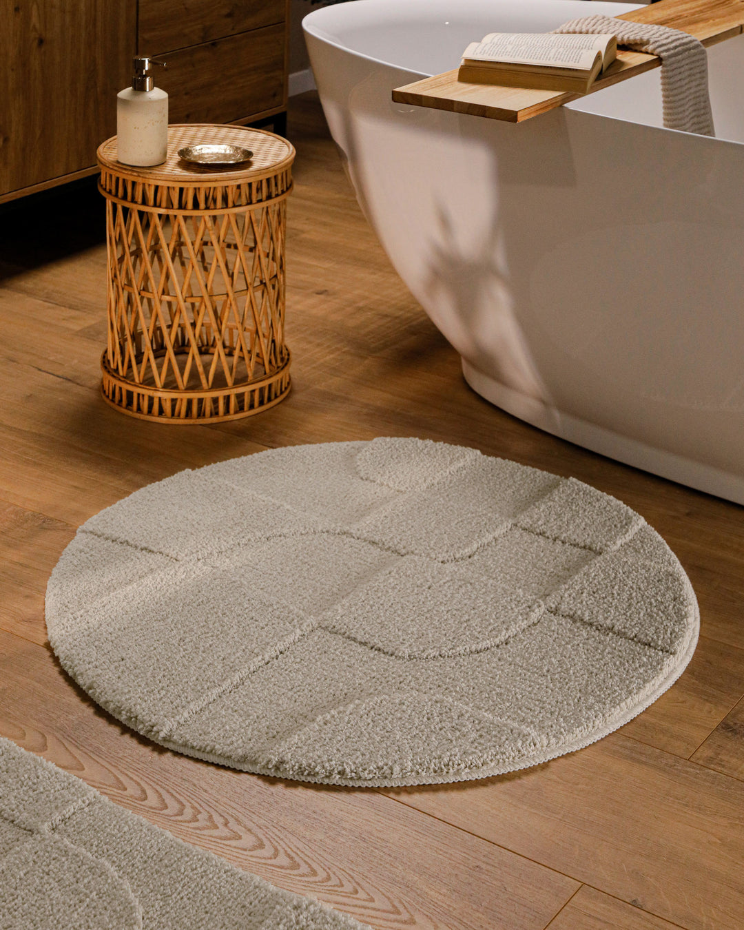Runder Badteppich Davie Grau im Badezimmer vor Badewanne auf Holzboden, strukturiertes Linienrelief im Flor sichtbar