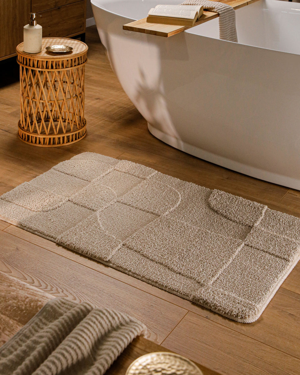 Badteppich Davie Sand Beige rechteckig im Badezimmer vor Badewanne auf Holzboden liegend, Strukturmuster im Flor sichtbar