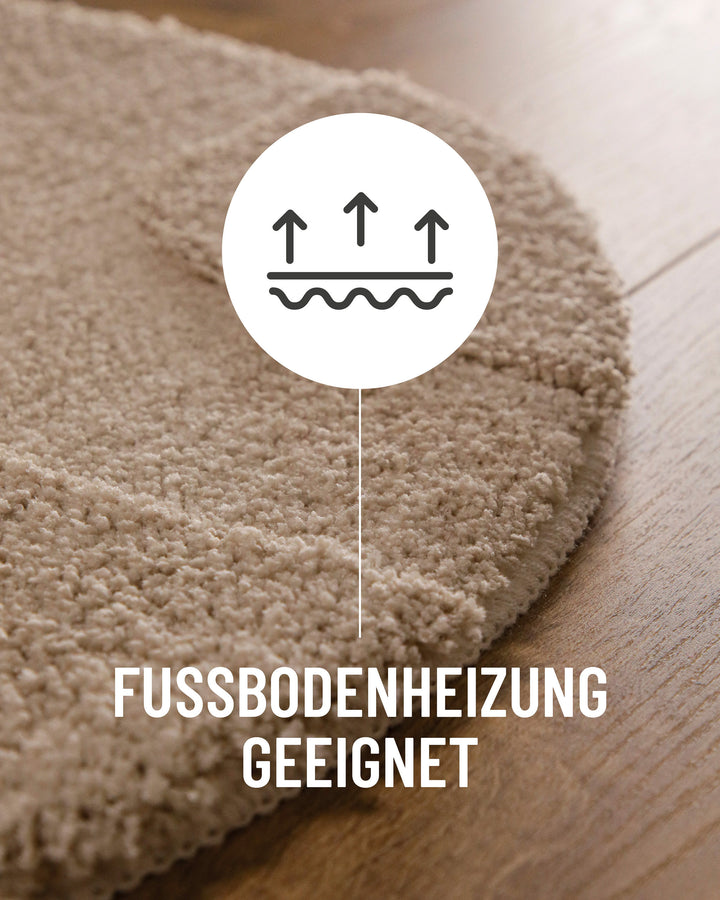 Badteppich Davie Sand Beige Detail der Teppichkante auf Holzboden, Symbol weist auf Eignung für Fußbodenheizung hin