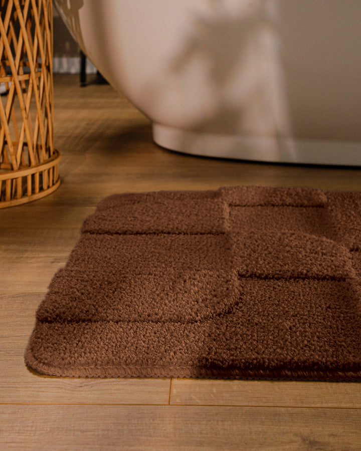 Badteppich Davie Braun runde Matte im Badezimmer vor Badewanne, Strukturmuster im Flor auf Holzboden sichtbar
