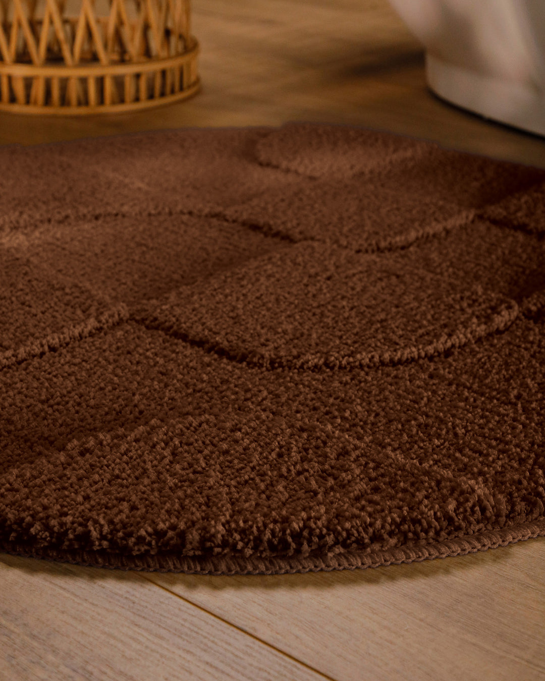 Badteppich Davie Braun rund im Badezimmer auf Holzboden neben Badewanne, Florstruktur und Linienrelief erkennbar