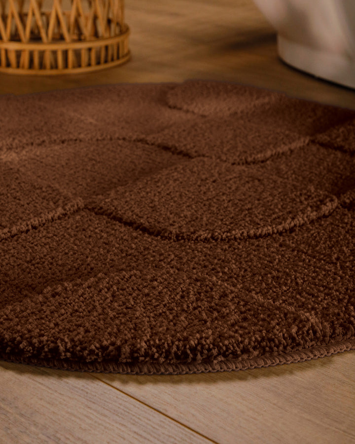 Badteppich Davie Braun rund im Badezimmer auf Holzboden neben Badewanne, Florstruktur und Linienrelief erkennbar