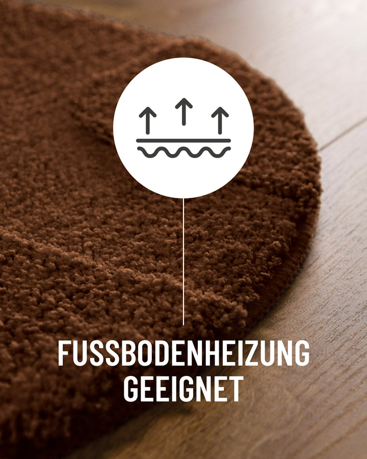 Badteppich Davie Braun Detail der Teppichkante auf Holzboden, Symbol weist auf Eignung für Fußbodenheizung hin