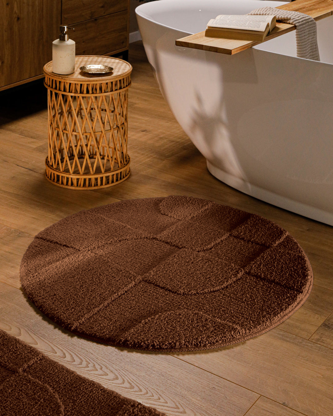 Runder Badteppich Davie Braun im Badezimmer vor Badewanne auf Holzboden, strukturiertes Linienrelief im Flor sichtbar