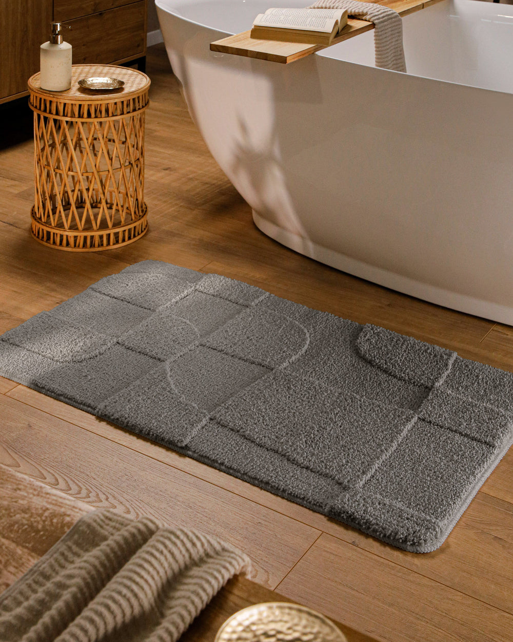 Badteppich Davie Basalt Grau rechteckig im Badezimmer vor Badewanne auf Holzboden liegend, Strukturmuster im Flor sichtbar