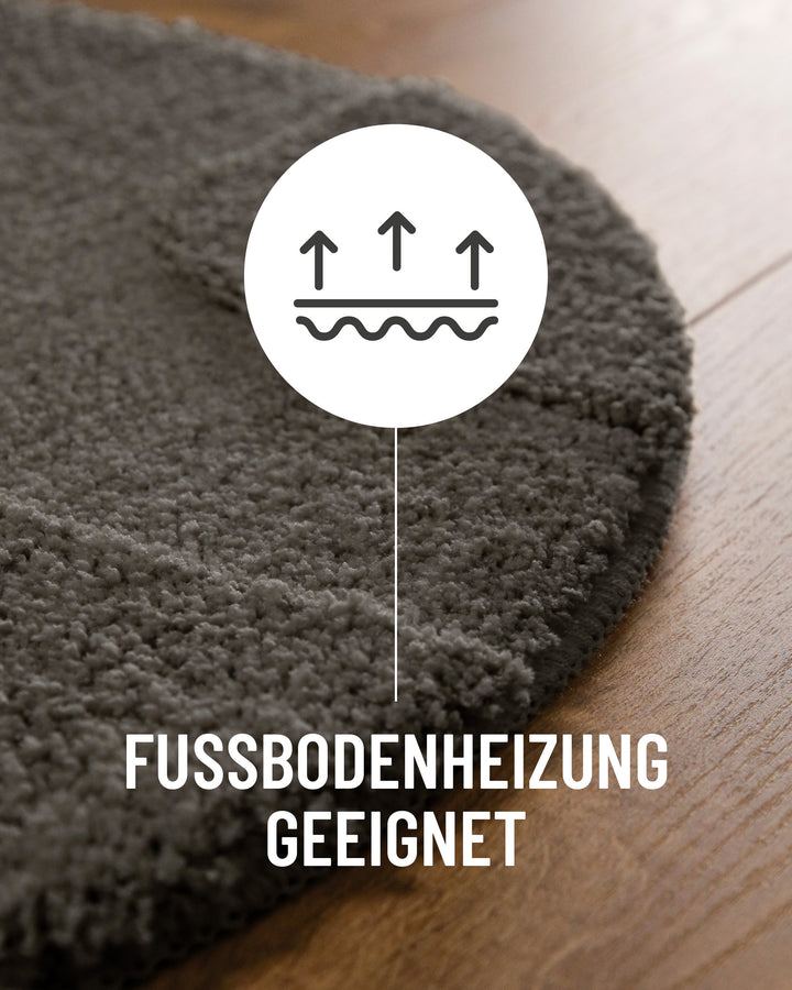 Badteppich Davie Basalt Grau Detail der Teppichkante auf Holzboden, Symbol weist auf Eignung für Fußbodenheizung hin