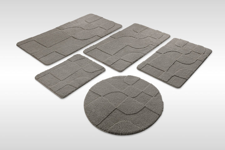 Badteppich Davie Basalt Grau Set aus rechteckigen und runden Badmatten, mehrere Größen auf hellem Hintergrund angeordnet