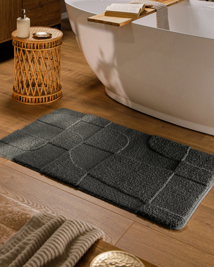 Badteppich Davie Anthrazit Grau rechteckig im Badezimmer vor Badewanne auf Holzboden liegend, Strukturmuster im Flor sichtbar