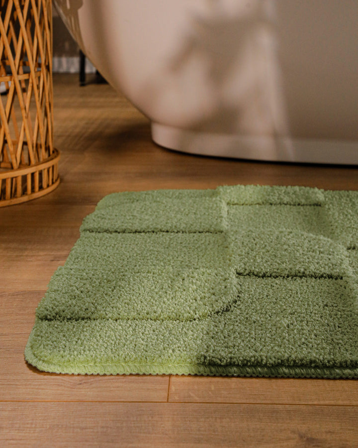Badteppich Davie Reseda Grün runde Matte im Badezimmer vor Badewanne, Strukturmuster im Flor auf Holzboden sichtbar