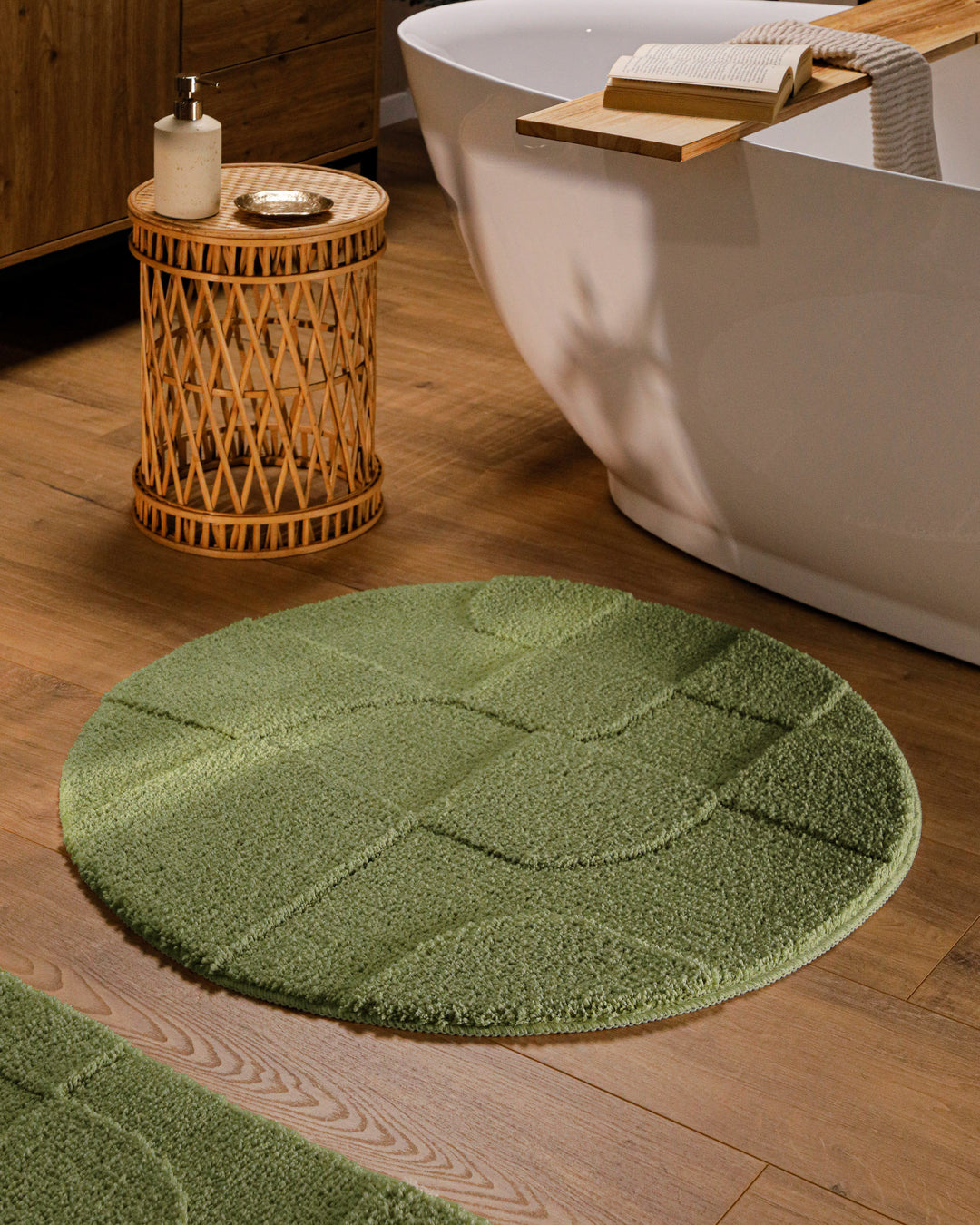 Runder Badteppich Davie Reseda Grün im Badezimmer vor Badewanne auf Holzboden, strukturiertes Linienrelief im Flor sichtbar