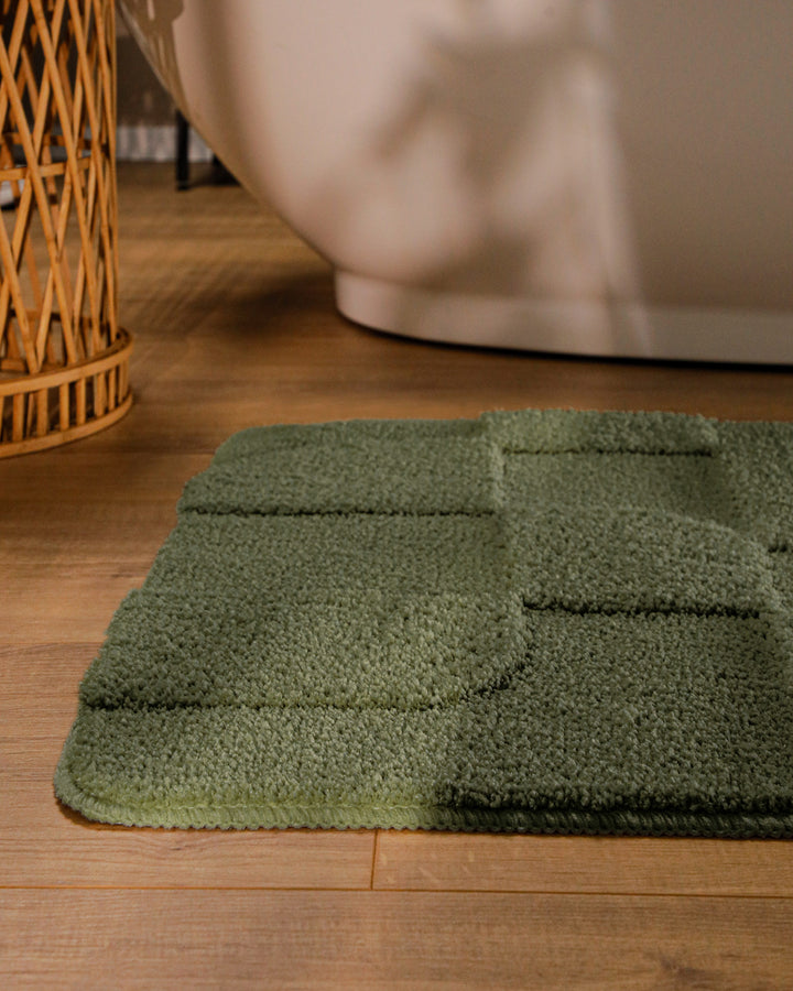 Badteppich Davie Kiefer Grün runde Matte im Badezimmer vor Badewanne, Strukturmuster im Flor auf Holzboden sichtbar