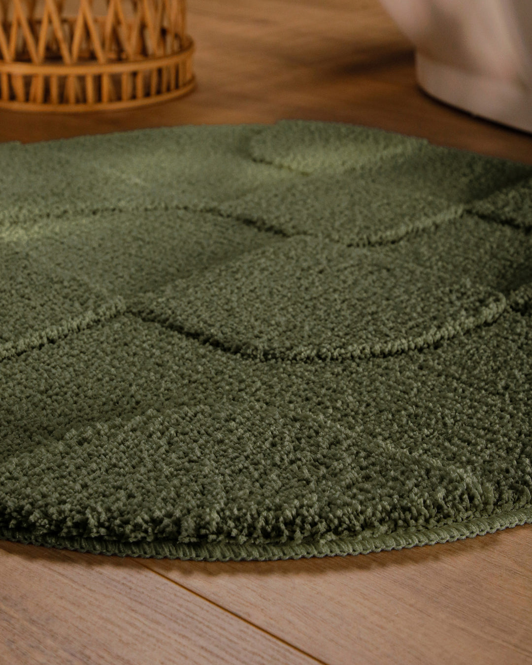 Badteppich Davie Kiefer Grün rund im Badezimmer auf Holzboden neben Badewanne, Florstruktur und Linienrelief erkennbar