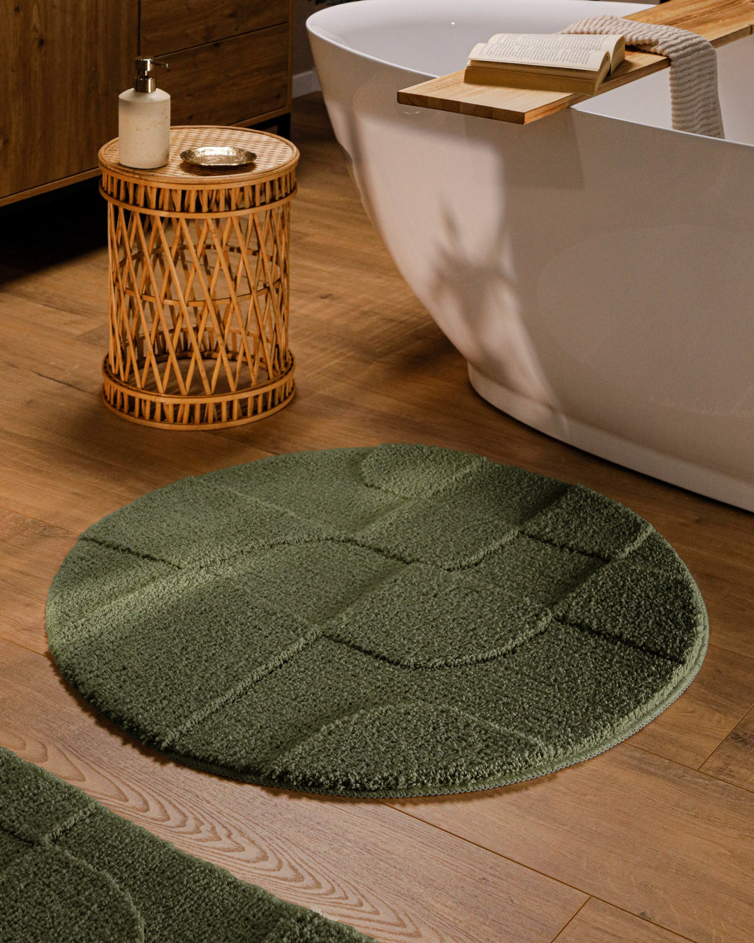 Runder Badteppich Davie Kiefer Grün im Badezimmer vor Badewanne auf Holzboden, strukturiertes Linienrelief im Flor sichtbar