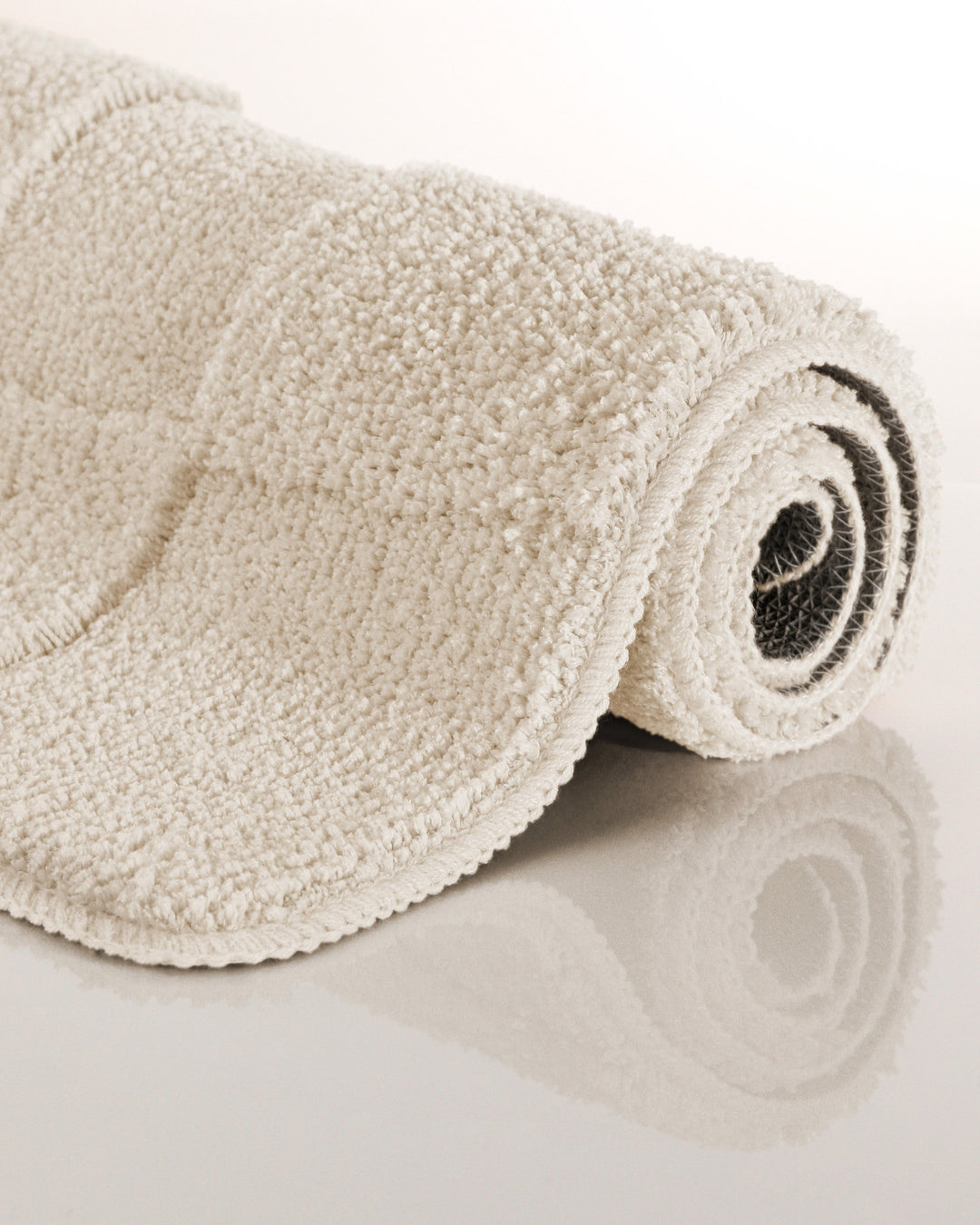 Badteppich Davie Creme Weiß aufgerollt auf hellem Hintergrund, Seitenansicht zeigt Florhöhe und Teppichkante
