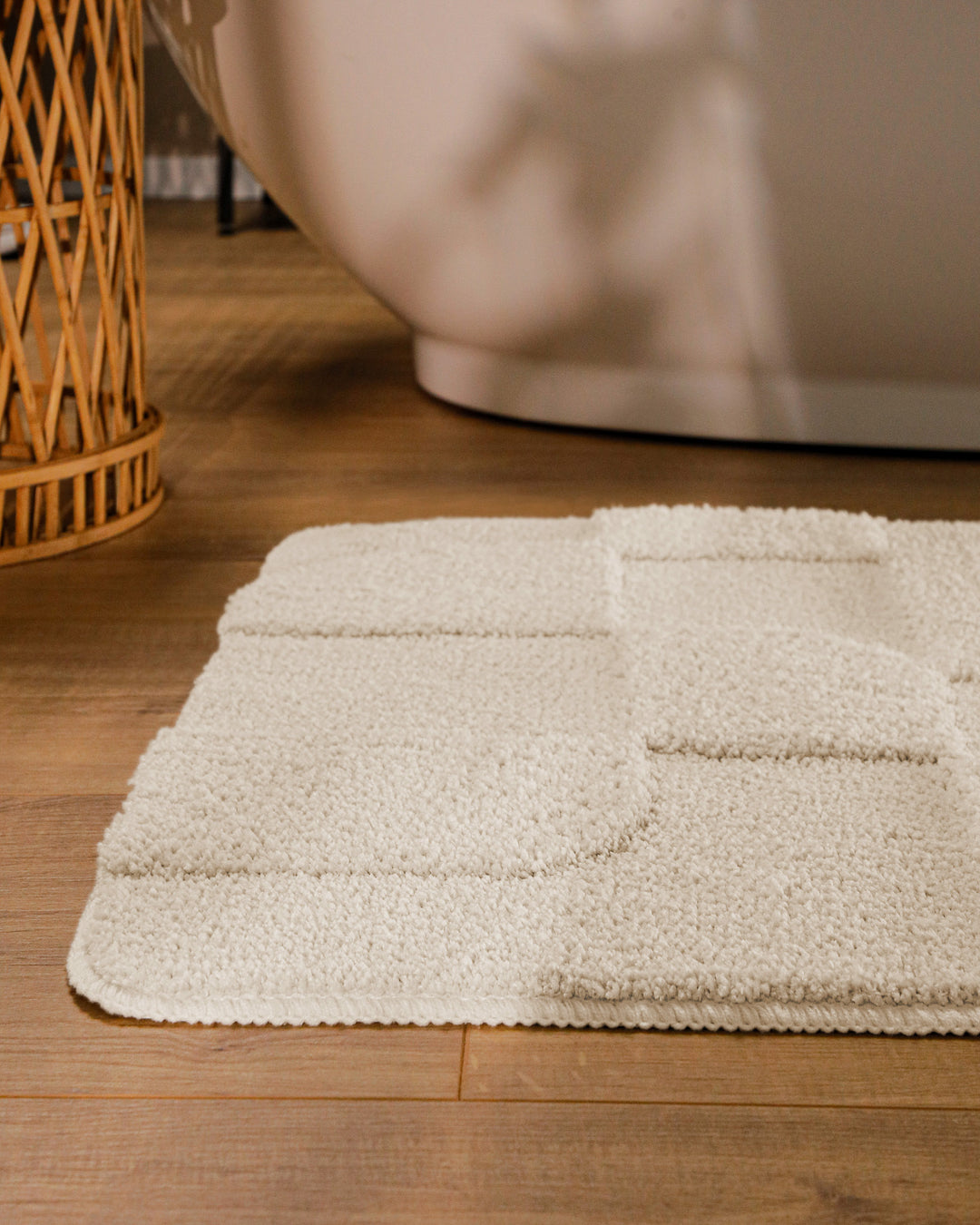 Badteppich Davie Creme Weiß runde Matte im Badezimmer vor Badewanne, Strukturmuster im Flor auf Holzboden sichtbar