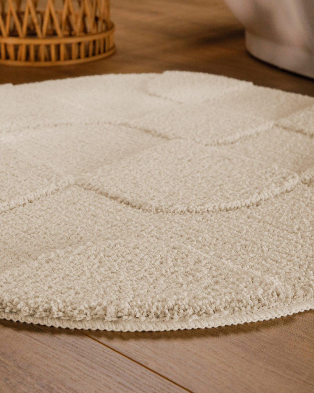 Badteppich Davie Creme Weiß rund im Badezimmer auf Holzboden neben Badewanne, Florstruktur und Linienrelief erkennbar
