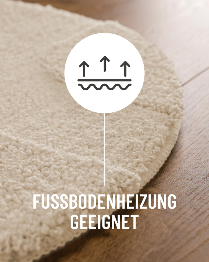 Badteppich Davie Creme Weiß Detail der Teppichkante auf Holzboden, Symbol weist auf Eignung für Fußbodenheizung hin