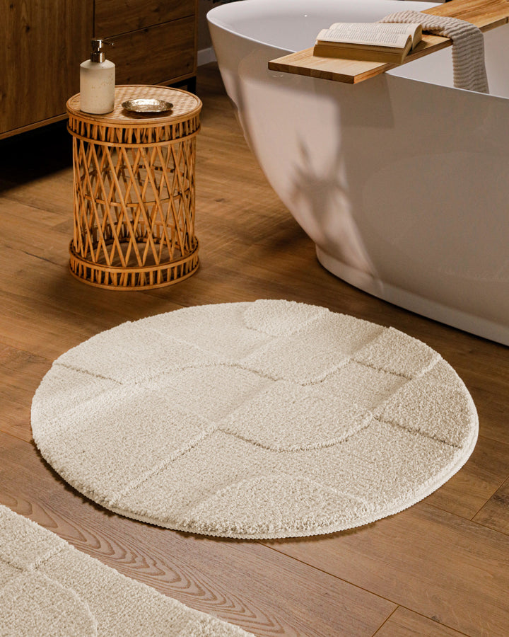 Runder Badteppich Davie Creme Weiß im Badezimmer vor Badewanne auf Holzboden, strukturiertes Linienrelief im Flor sichtbar