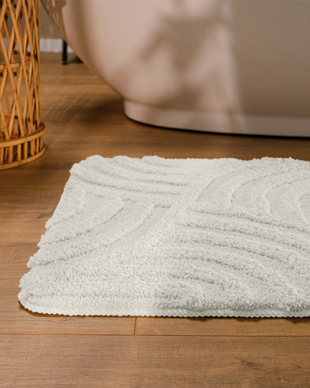 Badteppich Fiete Weiß runde Matte im Badezimmer vor Badewanne, Strukturmuster im Flor auf Holzboden sichtbar
