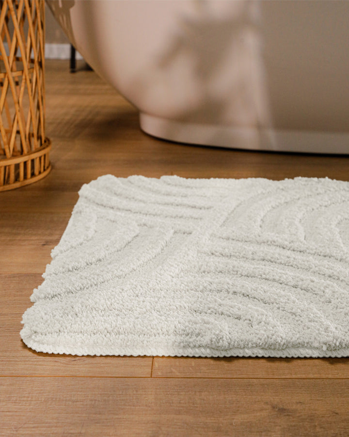 Badteppich Fiete Weiß runde Matte im Badezimmer vor Badewanne, Strukturmuster im Flor auf Holzboden sichtbar