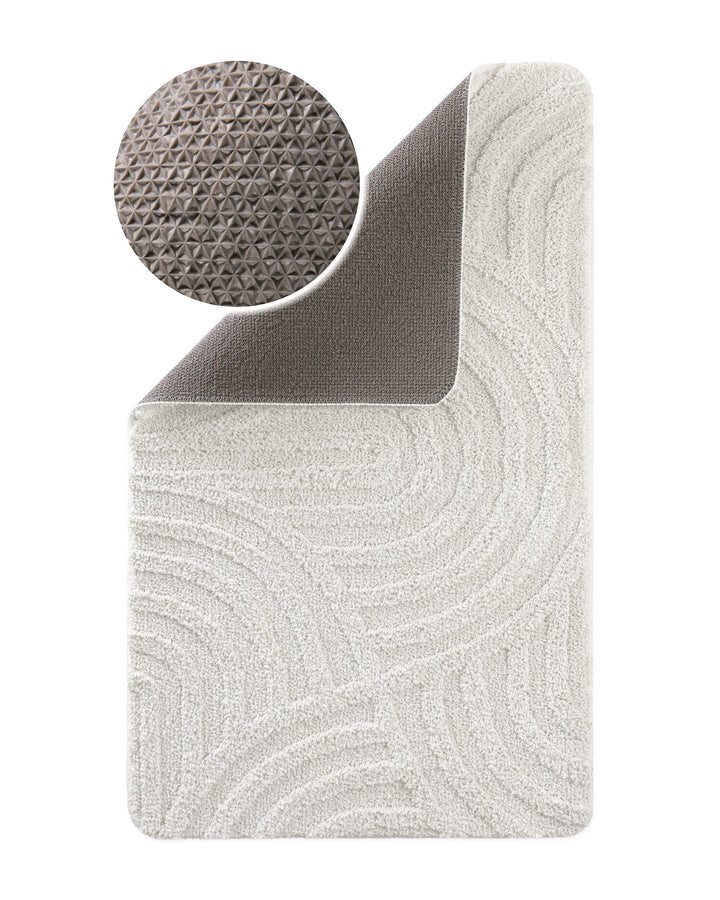 Badteppich Fiete Weiß Ecke hochgeklappt, runde Probe zeigt graue Rückseite mit rutschhemmender Beschichtung