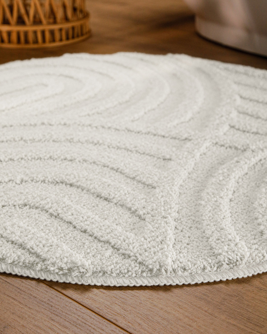 Badteppich Fiete Weiß rund im Badezimmer auf Holzboden neben Badewanne, Florstruktur und Linienrelief erkennbar