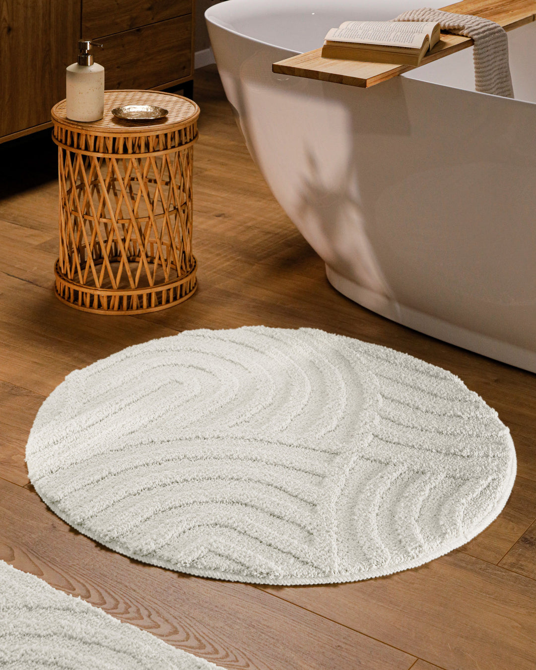 Runder Badteppich Fiete Weiß im Badezimmer vor Badewanne auf Holzboden, strukturiertes Linienrelief im Flor sichtbar