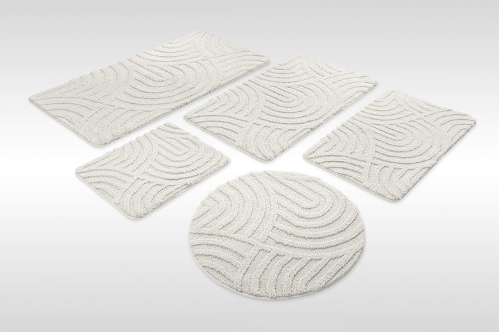 Badteppich Fiete Weiß Set aus rechteckigen und runden Badmatten, mehrere Größen auf hellem Hintergrund angeordnet