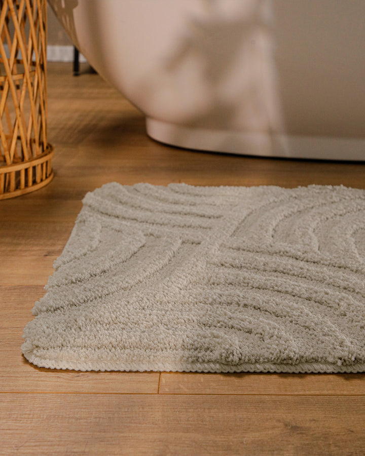 Badteppich Fiete Grau runde Matte im Badezimmer vor Badewanne, Strukturmuster im Flor auf Holzboden sichtbar