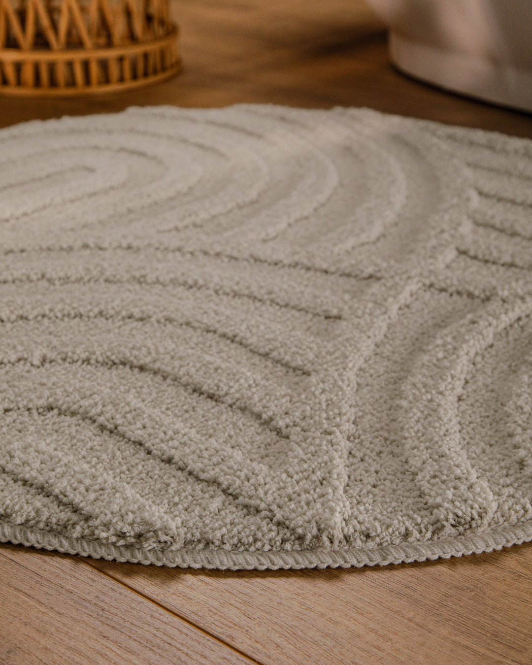 Badteppich Fiete Grau rund im Badezimmer auf Holzboden neben Badewanne, Florstruktur und Linienrelief erkennbar