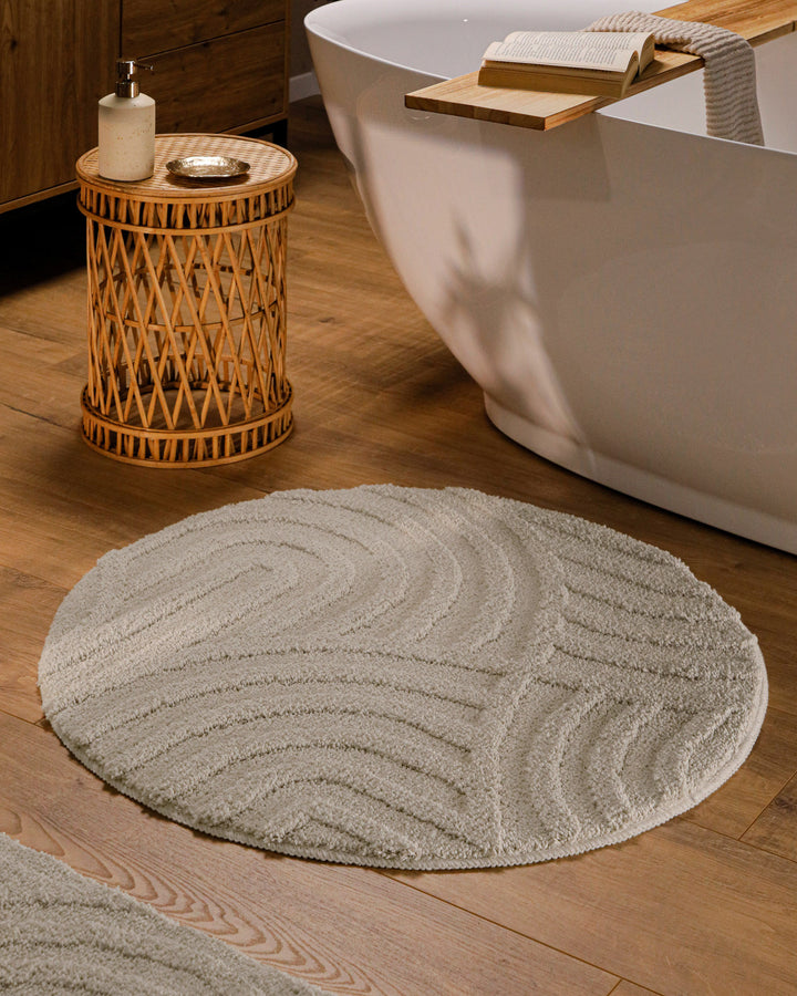 Runder Badteppich Fiete Grau im Badezimmer vor Badewanne auf Holzboden, strukturiertes Linienrelief im Flor sichtbar