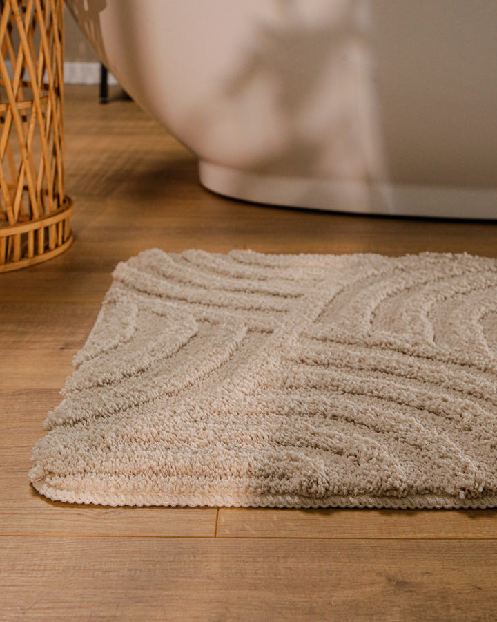 Badteppich Fiete Sand Beige runde Matte im Badezimmer vor Badewanne, Strukturmuster im Flor auf Holzboden sichtbar