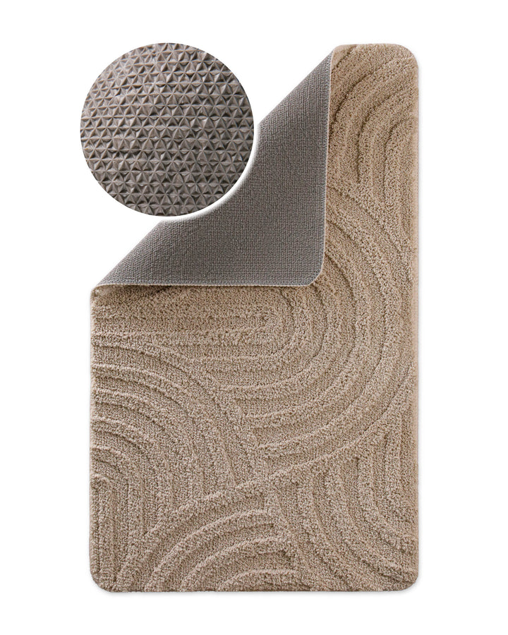 Badteppich Fiete Sand Beige Ecke hochgeklappt, runde Probe zeigt Sand Beigee Rückseite mit rutschhemmender Beschichtung