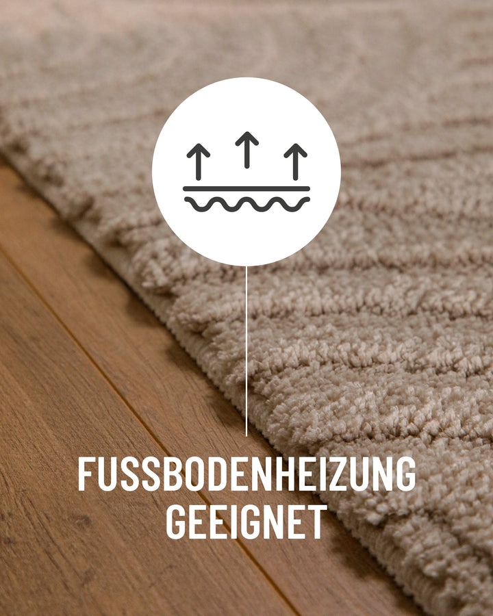 Badteppich Fiete Sand Beige Detail auf Holzfußboden mit Symbol für Fußbodenheizung, Nahaufnahme von Flor und Teppichkante