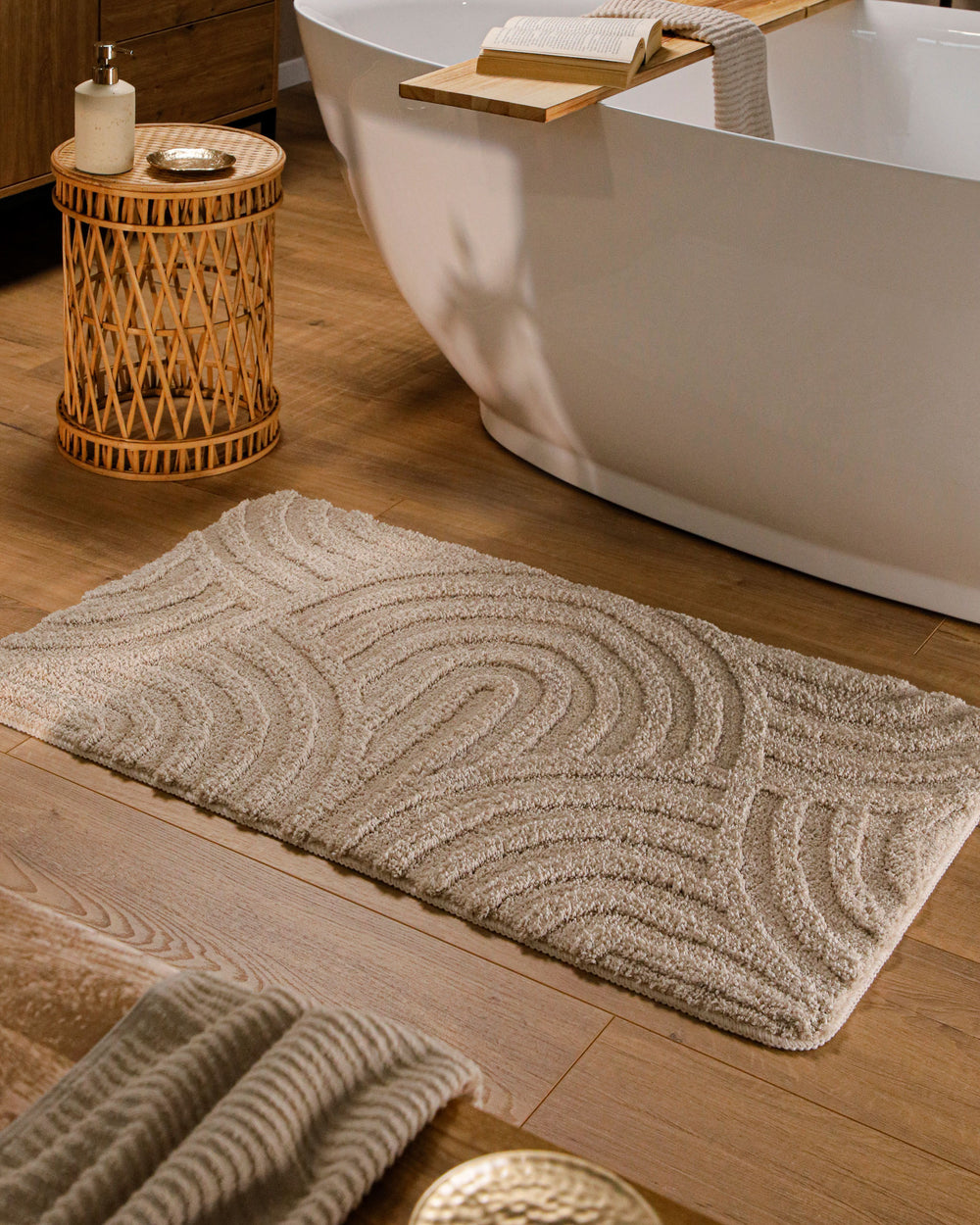 Badteppich Fiete Sand Beige rechteckig im Badezimmer vor Badewanne auf Holzboden liegend, Strukturmuster im Flor sichtbar