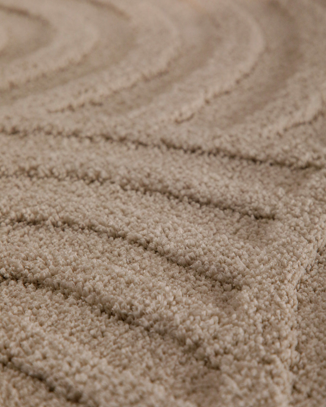 Badteppich Fiete Sand Beige rund Detail der Teppichkante mit Hinweisen zu maschinengetufteter Verarbeitung