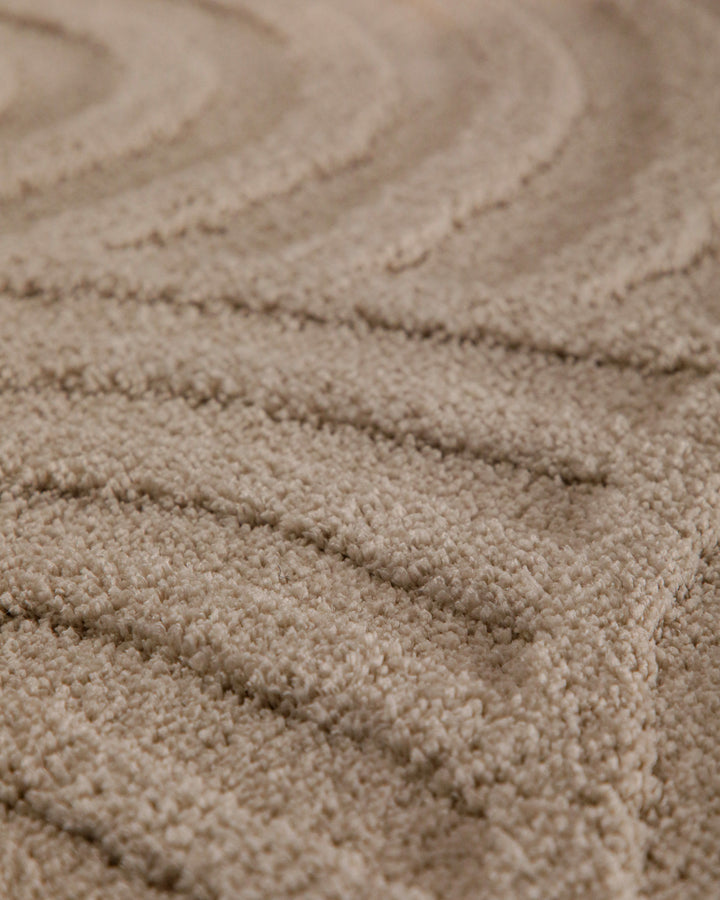 Badteppich Fiete Sand Beige rund Detail der Teppichkante mit Hinweisen zu maschinengetufteter Verarbeitung