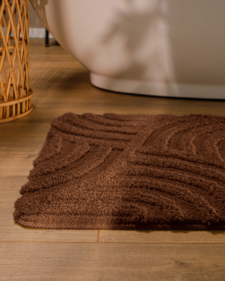 Badteppich Fiete Braun runde Matte im Badezimmer vor Badewanne, Strukturmuster im Flor auf Holzboden sichtbar