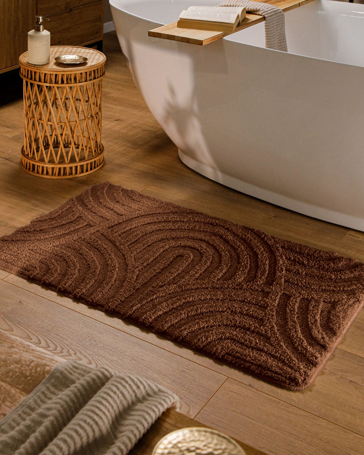 Badteppich Fiete Braun rechteckig im Badezimmer vor Badewanne auf Holzboden liegend, Strukturmuster im Flor sichtbar