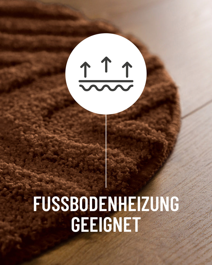 Badteppich Fiete Braun Detail der Teppichkante auf Holzboden, Symbol weist auf Eignung für Fußbodenheizung hin