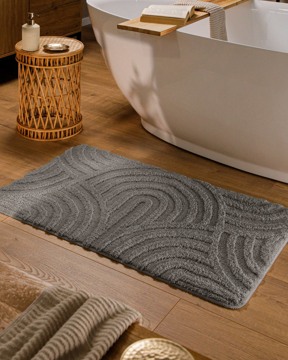 Badteppich Fiete Basalt Grau rechteckig im Badezimmer vor Badewanne auf Holzboden liegend, Strukturmuster im Flor sichtbar