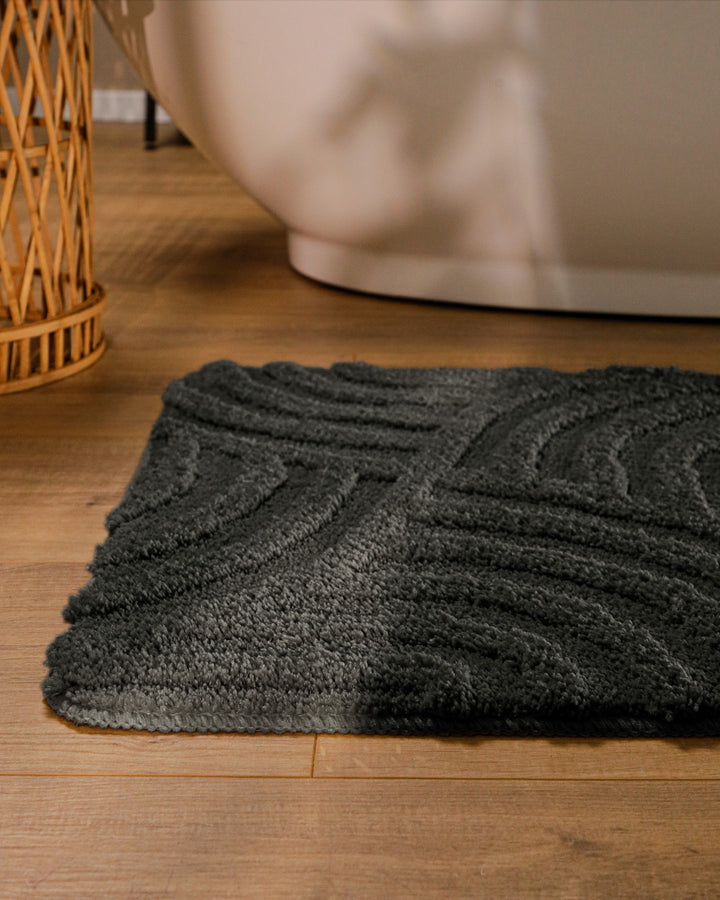 Badteppich Fiete Anthrazit Grau runde Matte im Badezimmer vor Badewanne, Strukturmuster im Flor auf Holzboden sichtbar