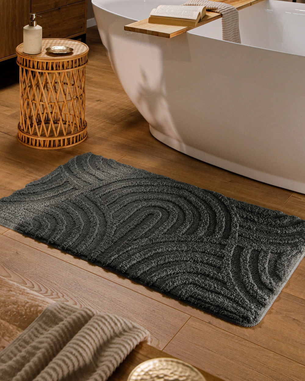 Badteppich Fiete Anthrazit Grau rechteckig im Badezimmer vor Badewanne auf Holzboden liegend, Strukturmuster im Flor sichtbar